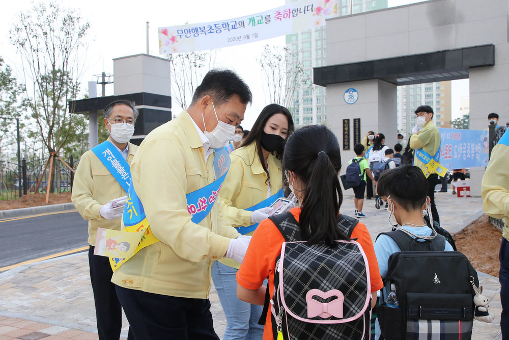 행복초등학교 정문에서 학생들에게 수첩을 나눠주고 있는 무안 군수