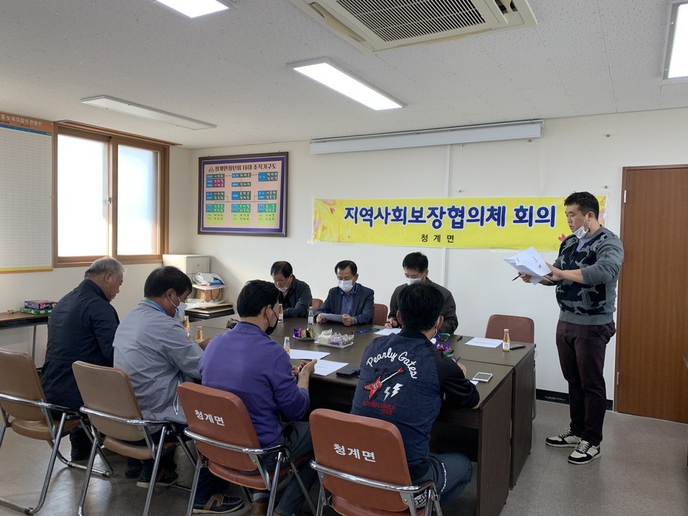 청계면 지역사회보장협의체 정기회의 개최되고 있고 사람들이 마스크를 쓰고 종이를 보고있는 모습