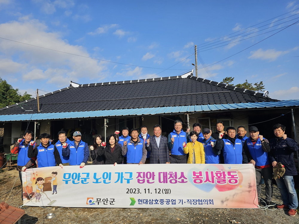 삼호중공원기직장협의회 봉사활동 회원들이 집앞마당에서 현수막(무안군 노인가구 집안대청소 봉사활동 2023.11.12(일) 무안군, 현대삼호중공업 기 직장협의회)을 들고 단체 기념촬영을 하는 모습