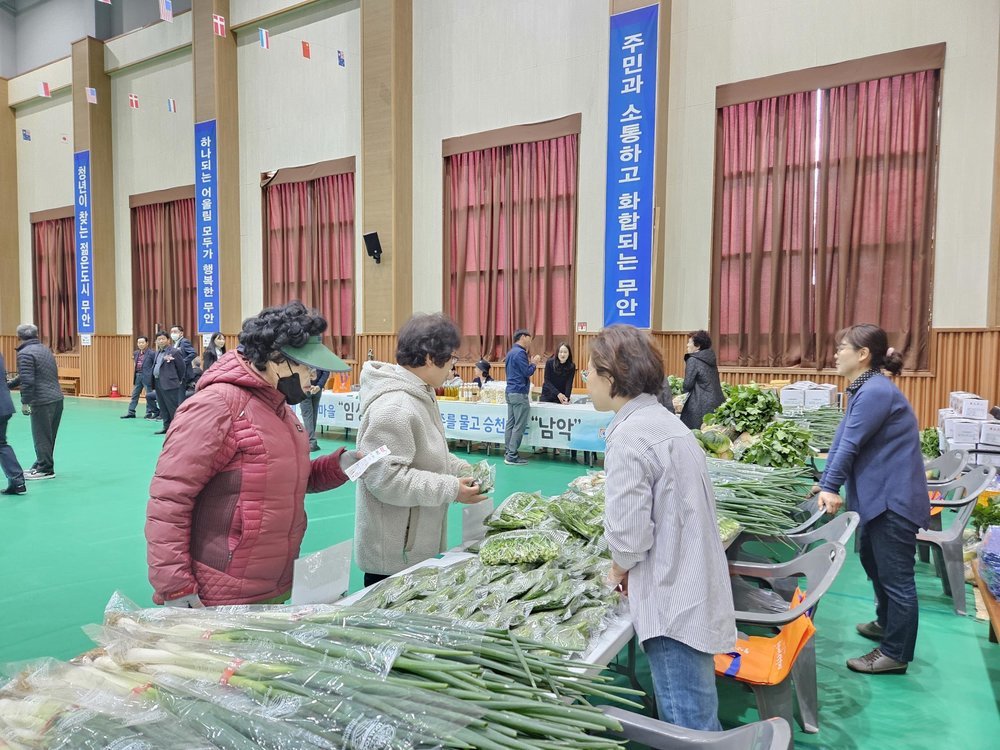 다양한 야채가 진열되어있는 도농교류행사장에서 사람들이 채소들을 둘러보고 있는 모습